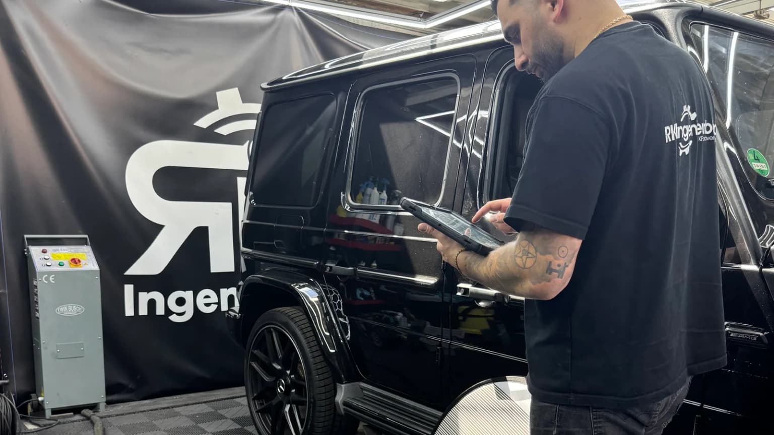 Unabhängiger Kfz-Sachverständiger prüft Gutachtenwerte am Tablet neben dem Fahrzeug